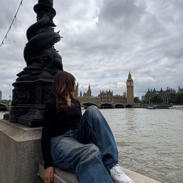 Thames kıyısında oturan öğrenci, arka planda Westminster